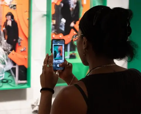 A silhouette of a woman taking photos of works in the exhibition space.